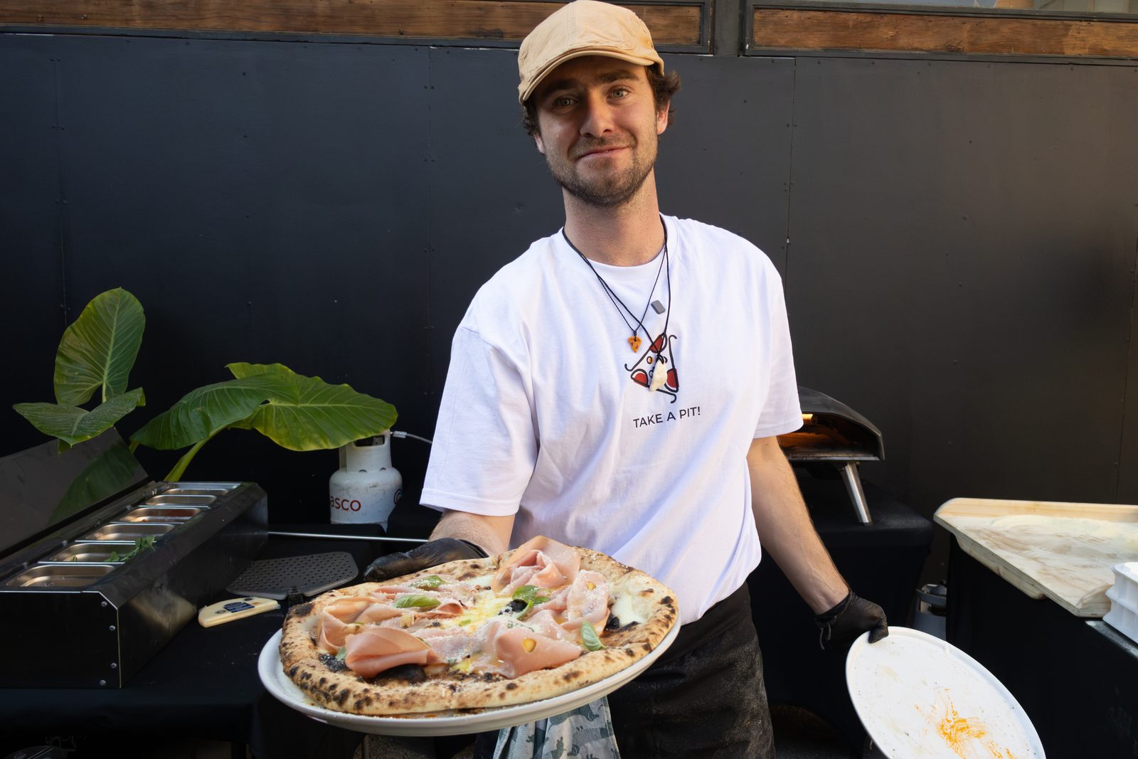Pedro sosteniendo una pizza recién horneada